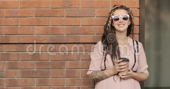 幸福的年轻孕妇的肖像站在砖墙附近喝咖啡视频的预览图