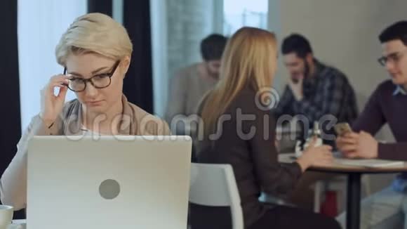 美丽的年轻商务女性微笑的肖像戴着眼镜坐在Woth笔记本电脑咖啡馆里视频的预览图