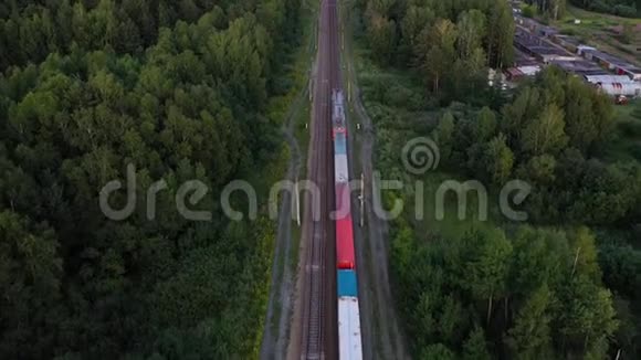 货运列车的鸟瞰图载着碎石和水泥日落时分穿过森林无人驾驶飞机的4K镜头视频的预览图