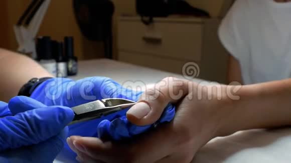美甲师在女孩手的手指上切割角质层摩尼教大师正在为美容院的顾客做美甲视频的预览图