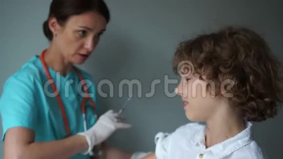 医生助理给一个卷毛男孩接种疫苗流感疫苗接种免疫计划医药和保健概念视频的预览图