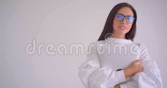 年轻漂亮的白种人女商人戴着眼镜拿着笔记本电脑看着镜头微笑的特写照片视频的预览图