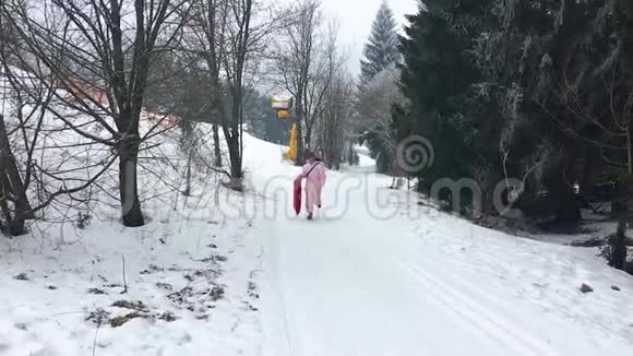 成人带着雪橇跑上雪山成人和儿童都喜欢的玩具冬季运动和乐趣视频的预览图