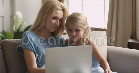 快乐的妈妈和可爱的小女儿玩笔记本电脑视频的预览图