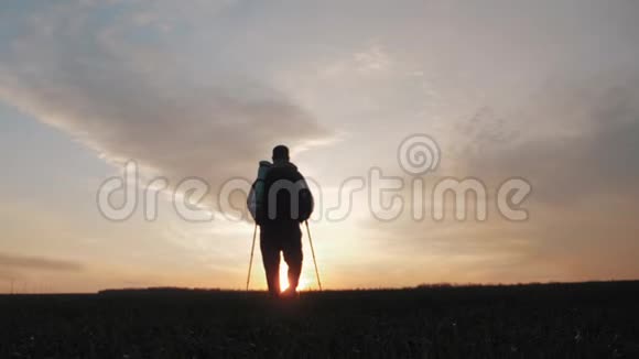 剪影徒步旅行者与背包跟踪和徒步杆在日落的背景与大自然独处健康视频的预览图
