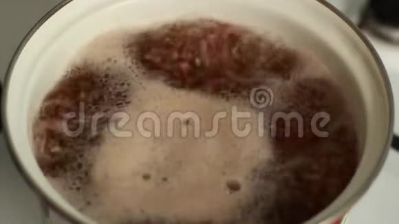 荞麦在厨房里煮沸腾的水蒸气从平底锅中取出和捕获多余的泡沫午餐烹饪视频的预览图