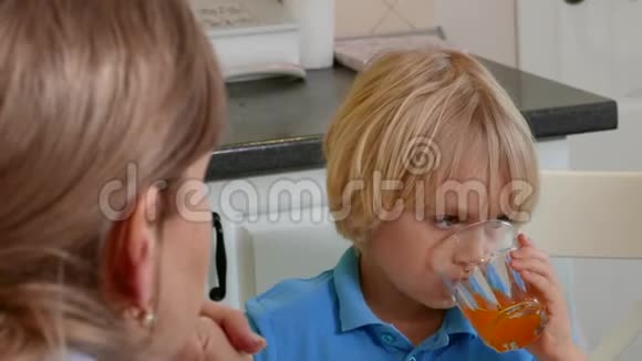 小可爱的男孩从杯子里喝果汁视频的预览图