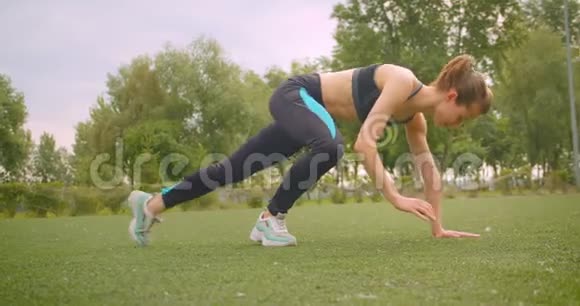 城市户外公园里年轻漂亮运动健身女孩做侧木板运动的特写镜头视频的预览图