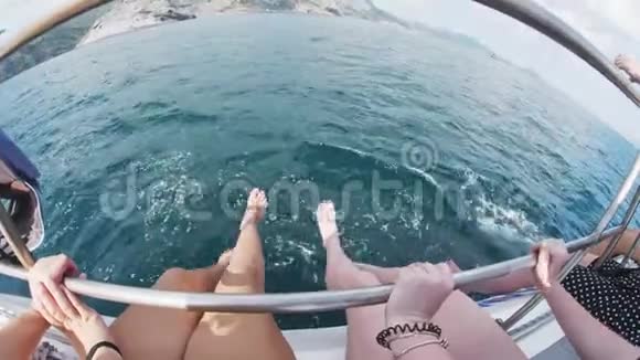 女人双脚欢快地摇摆着拍打着从船舷上航行的海浪视频的预览图