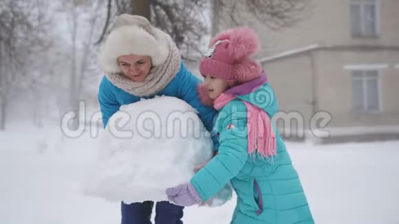 妈妈和两个女儿雕刻雪人一个幸福的家庭在冬天在外面堆雪人视频的预览图