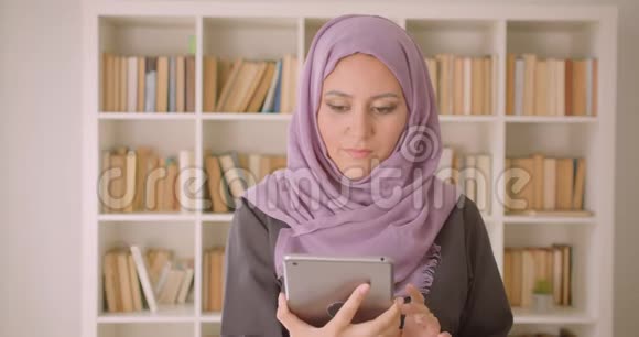 用平板电脑拍摄阿拉伯年轻漂亮女性在头巾上的特写肖像并在镜头中显示绿色彩色屏幕视频的预览图