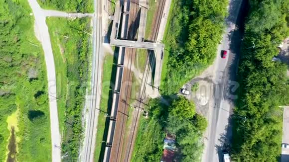 从上到下的空中俯瞰铁路和火车站周围是公园和田野阳光下有绿草和秋色的树木视频的预览图
