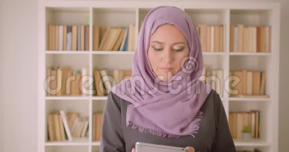 使用平板电脑特写穆斯林年轻漂亮女性的照片并在镜头中显示绿色彩色屏幕视频的预览图