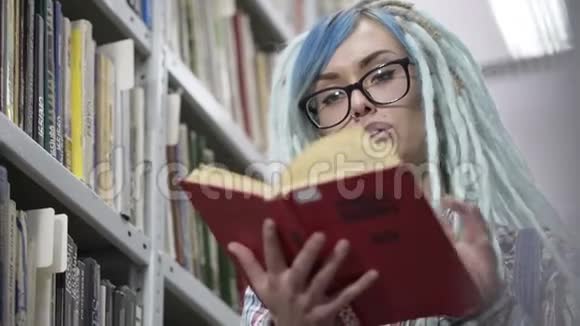 在图书馆里看红色书籍的时髦女人的特写肖像视频的预览图
