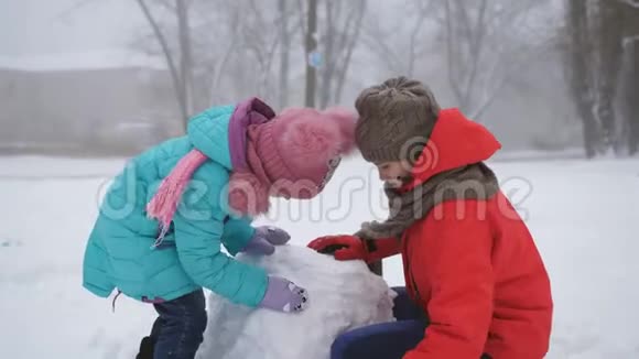年长的和年轻的姐妹带着乐趣在街上堆雪人视频的预览图