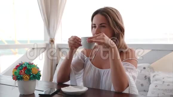 在海滨餐馆喝咖啡的快乐年轻美女的肖像视频的预览图