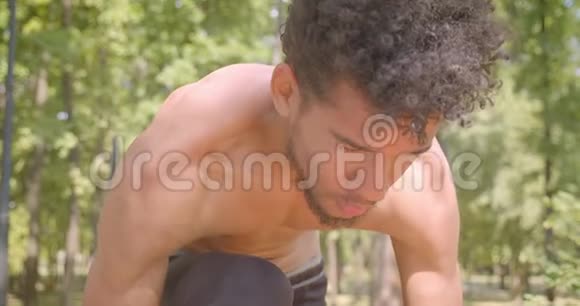 年轻的赤膊非洲男性慢跑者正准备在户外公园跑步的特写镜头视频的预览图