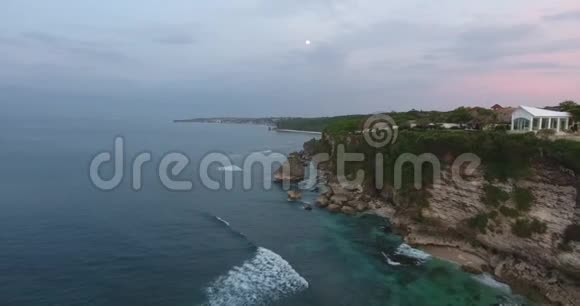 美丽的鸟瞰巴厘岛海岸有一个大规模的度假胜地晚上4k视频的预览图