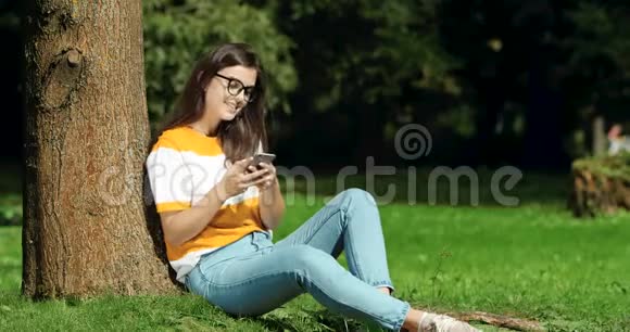妇女在公园浏览智能手机视频的预览图