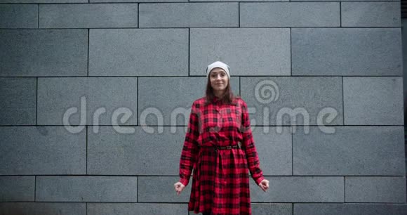 穿红色衣服的女人在城市混凝土墙旁边的街道上傻乎乎地跳舞视频的预览图