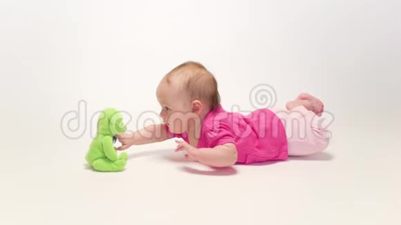 可爱的女婴在白色背景上玩软玩具视频的预览图