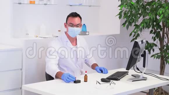 在办公桌前穿着白大褂的男实验室工作人员视频的预览图