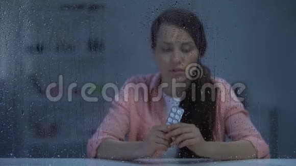 患有致命疾病的妇女在雨窗后拿着药丸视频的预览图