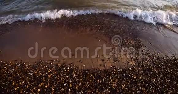 框架沿海岸的运动波浪慢慢地冲到海滩的岩石海岸上视频的预览图
