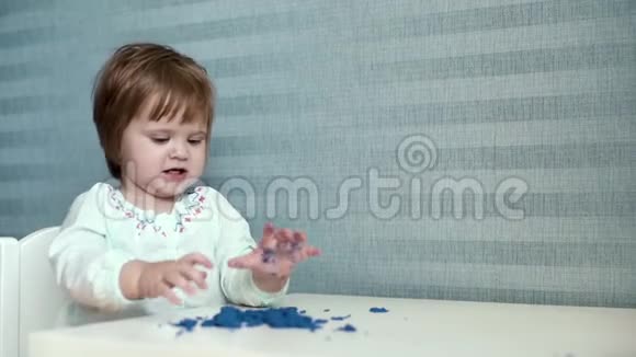 小女孩缓慢地从桌子上往地板上扔动能沙子视频的预览图
