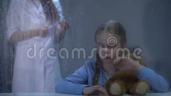 害怕的女孩拿着玩具熊背景上有注射器的护士雨天视频的预览图