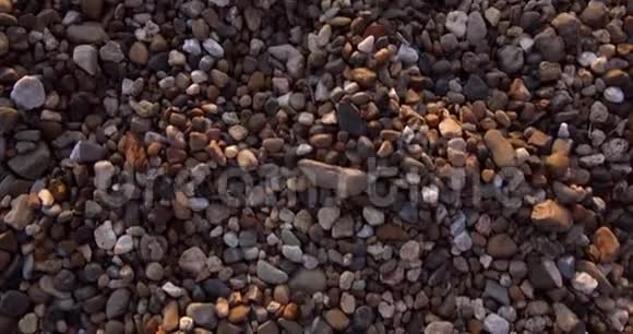 海岸上多种颜色的石头小圆石的纹理在框架中的移动视频的预览图