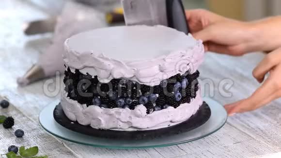 女人的手用烹饪的铲子用紫色奶油做饼干蛋糕视频的预览图