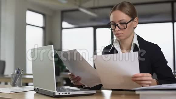 年轻女子在办公室偷偷看杂志懒惰的员工逃避工作视频的预览图