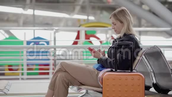 女旅客在车站候车室休息坐着用电话视频的预览图
