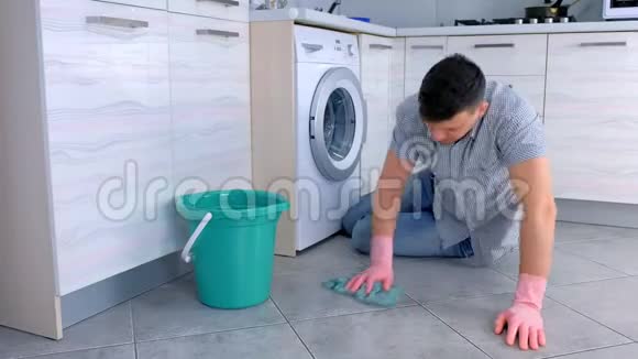 穿着橡胶手套的累人在厨房里洗和擦地板坐在地板上视频的预览图