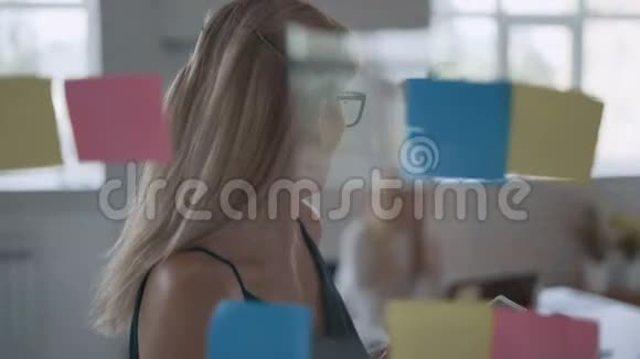 现代成功的金发女人在办公室里做一个项目女人站在透明板前面上面写着纸条视频的预览图