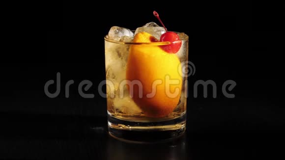 老式鸡尾酒用糖糖冰块和波旁威士忌旋转的岩石玻璃在黑桌上玻璃冷却了视频的预览图