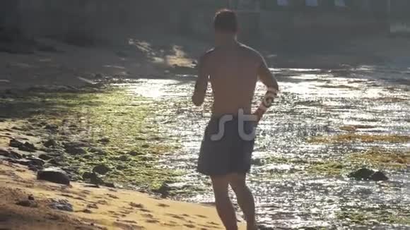 强壮的人沿着黄沙和棕色的岩石慢慢地奔跑视频的预览图