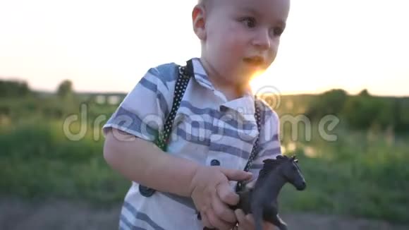 可爱的男孩拿着一个小马玩具在日落时快乐地在路上奔跑视频的预览图