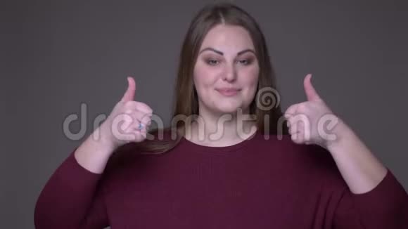 年轻的超重白种人女性在看背景镜头时竖起大拇指微笑视频的预览图