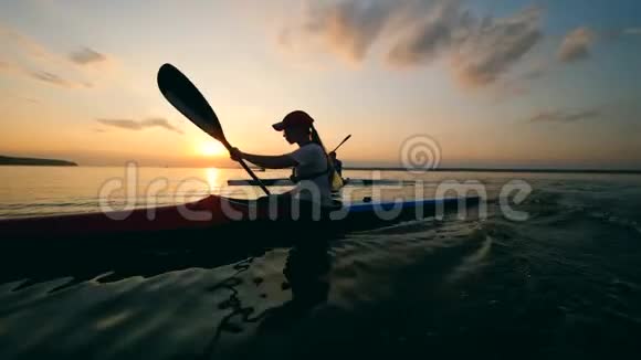 一个女人正划着船划过日落湖视频的预览图