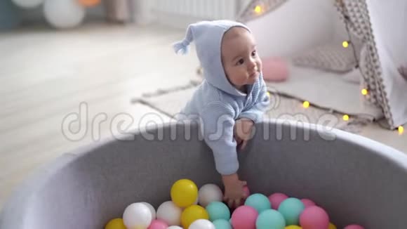 一个快乐可爱的宝宝从游泳池里扔出五颜六色的球视频的预览图