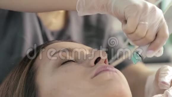 一位美容师实施了一个程序来操纵一个女人面对缓慢的运动时的滑水装置视频的预览图