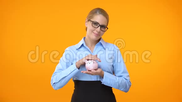 持有储蓄罐养老基金存款保险的女性银行经理视频的预览图