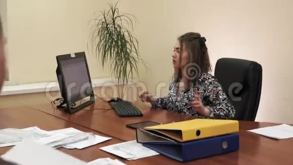 年轻的女商人坐在办公室的办公桌前从一名雇员那里拿文件视频的预览图