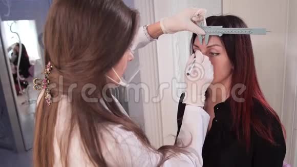 美容院专家测量一个漂亮女孩眉毛之间的距离4K慢慢视频的预览图