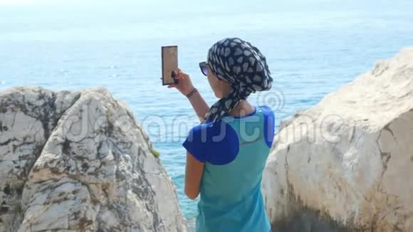 年轻的女旅行者站在岩石上拍照视频的预览图