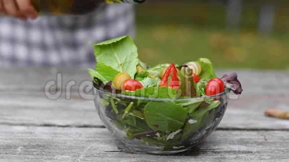 做纯素沙拉女人正在慢慢地在碗里的蔬菜沙拉里浇油视频的预览图