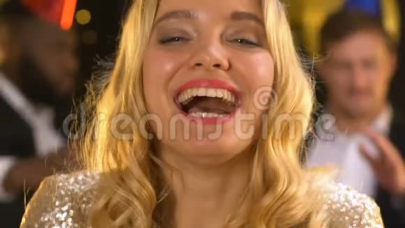 快乐微笑的女士吹着纸屑在生日聚会上做空气亲吻视频的预览图