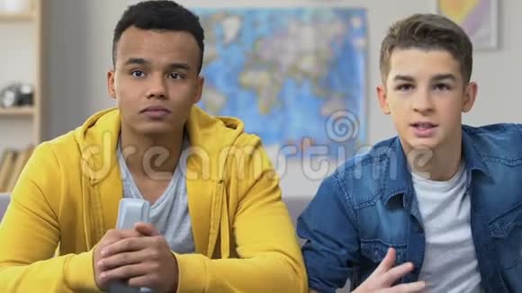 两个十几岁的朋友在电视上看体育节目最喜欢的球队输了球迷男孩心烦意乱视频的预览图